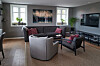 Moderne stue med sofaer, lenestoler, TV, planter og stort kunstverk på veggen.