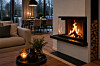 Moderne stue med tent peis, sofa, salongbord og spisebord foran store vinduer.